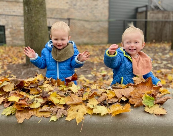 two young boys playing in the autumn leaves
