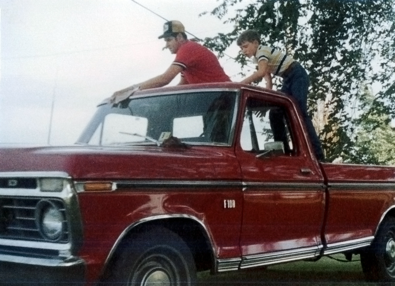 Treasurer Frerichs as a boy with his dad, standing in the bed of a red truck as they wash and wax it