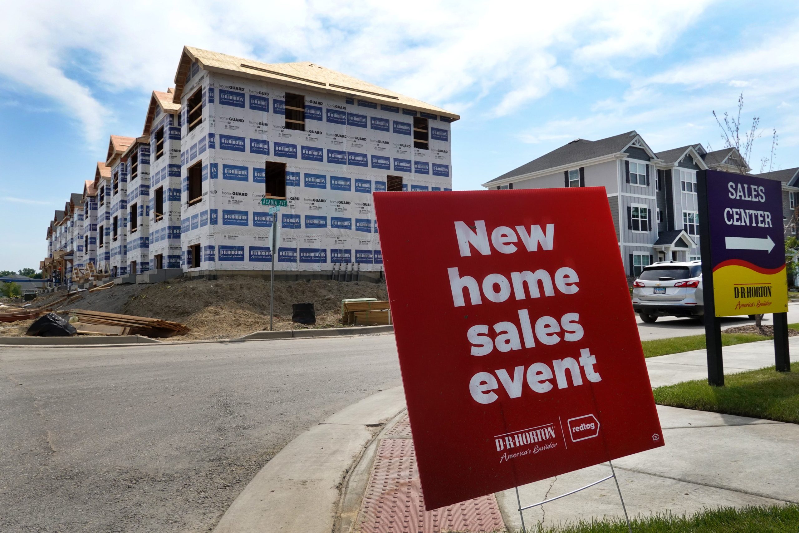 a new home sales event sign in front of a building