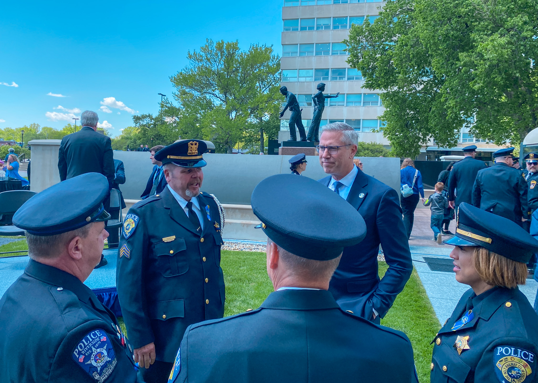 Treasurer Frerichs speaks with four uniformed police officers near the Police Memorial at the Illinois State Capitol