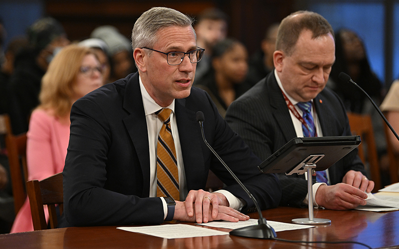 Treasurer Frerichs seated at a table and speaking into a microphone